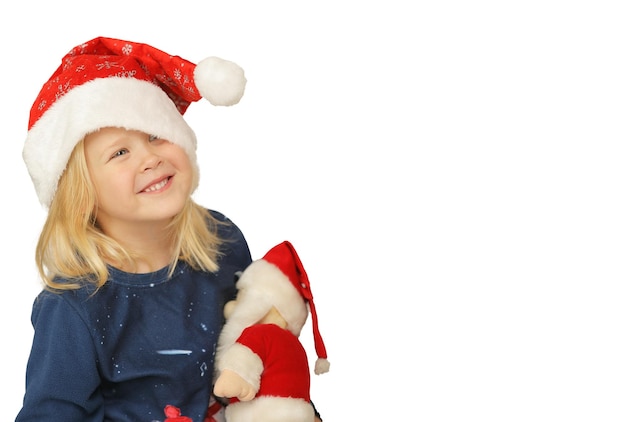 Linda chica con sombrero de santa está emocionada sosteniendo un juguete de navidad sobre fondo blanco.