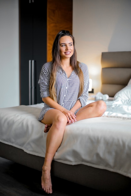 Linda chica sonriente y sentada en la cama