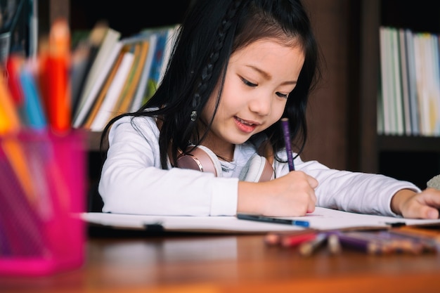 linda chica sonrió y se sienta a dibujar un libro en la biblioteca