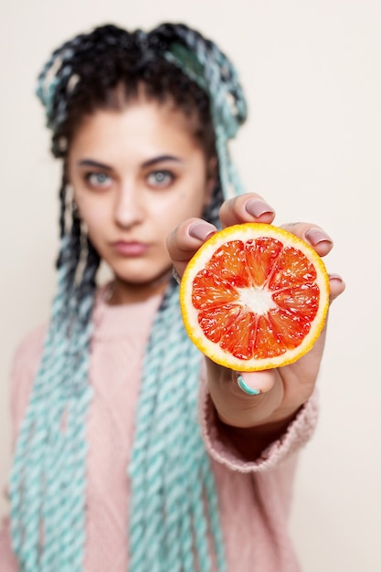Linda chica sosteniendo la mitad de una naranja roja