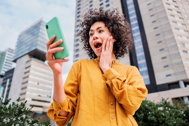 Linda chica sosteniendo un teléfono inteligente en la mano sorprendió a una joven viendo una celda