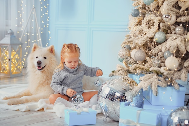 Linda chica con su perro decorando el árbol de Navidad en casa.