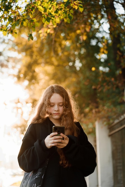 linda chica con teléfono inteligente en el parque de otoño.