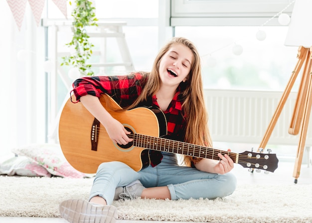 Linda chica tocando la guitarra sentado en el piso