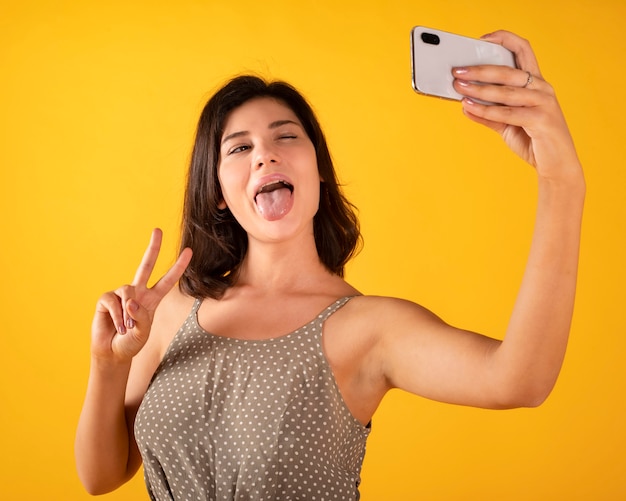 Linda chica toma una selfie con el teléfono, espacio amarillo