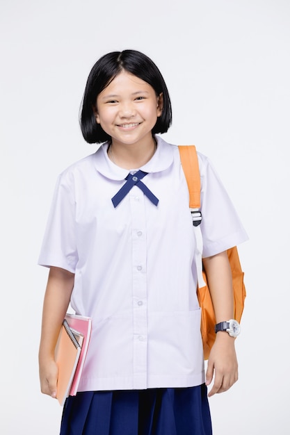 Linda chica en uniforme de estudiante con papelería en gris