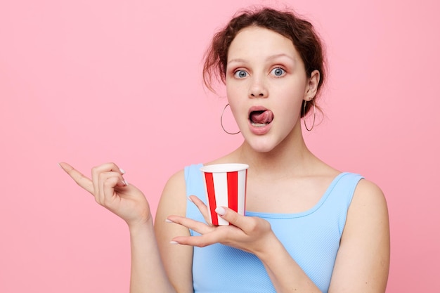 Linda chica con vaso desechable de bebida fondo rosa inalterado