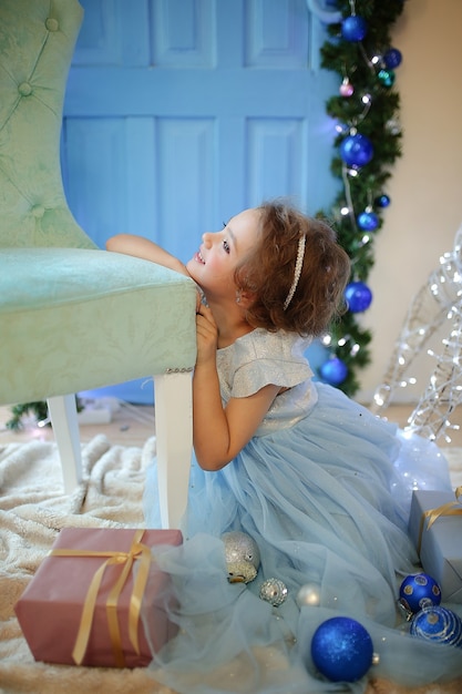 Linda chica con un vestido azul con bolas de Navidad en la víspera de la fiesta de 2022