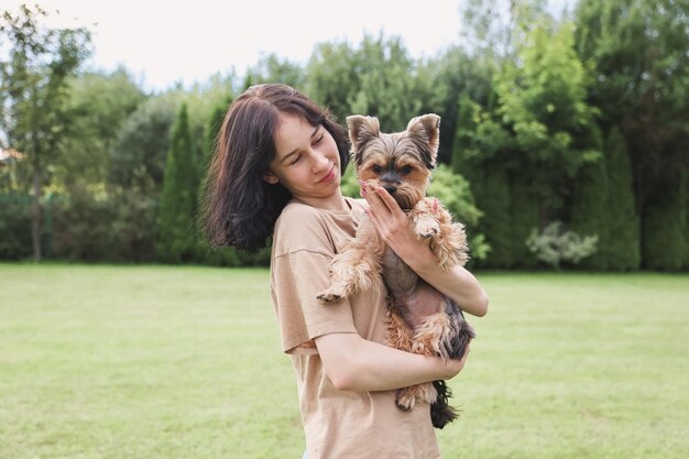 Una linda chica con un Yorkshire terrier en la calle Abrazos con tu perrito en el parque