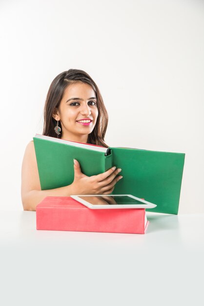 Linda colagem indiana asiática. Menina estudando em um tablet com uma pilha de livros