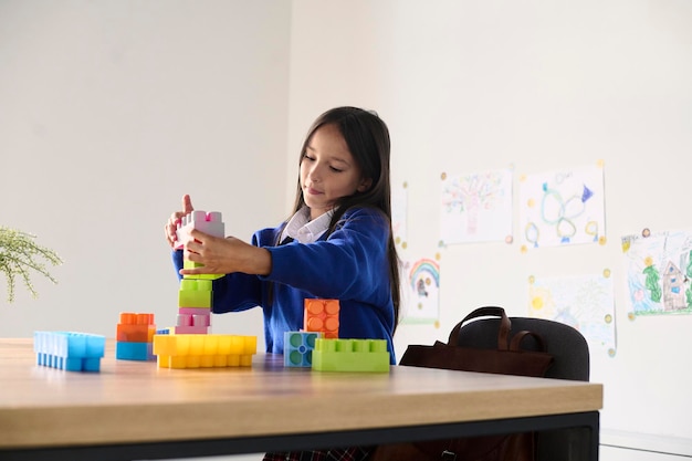 Una linda colegiala jugando en el escritorio del salón de clases