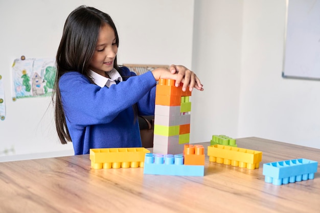 Una linda colegiala jugando en el escritorio del salón de clases