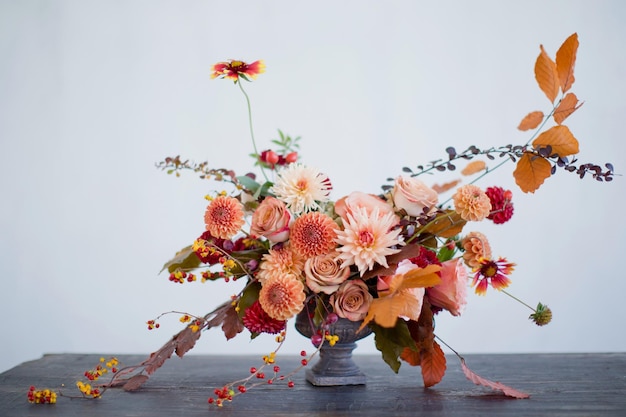 Linda composição de flores com flores e bagas laranja e vermelhas de outono Buquê de outono em vaso vintage em um fundo de parede branca