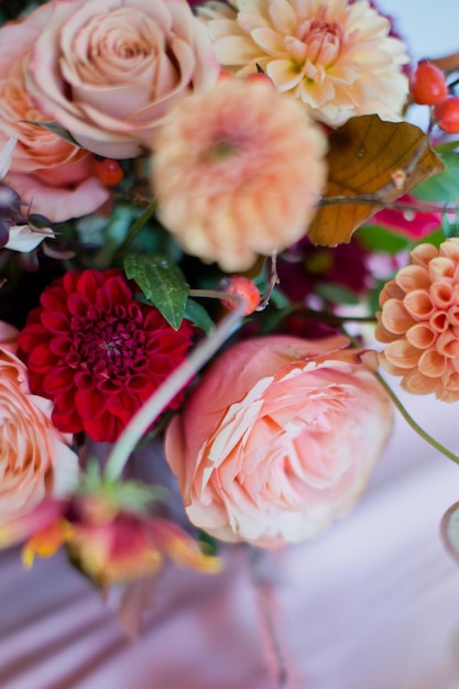 Linda composição de flores com flores e bagas laranja e vermelhas de outono Buquê de outono em vaso vintage em uma mesa de madeira com tecido rosa