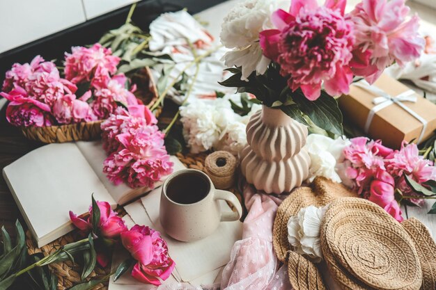 Linda composição de primavera conceito de bom dia Xícara de peônias de chá e livro aberto