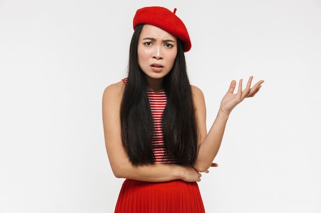 linda confusa jovem muito asiática posando isolado sobre uma parede branca.