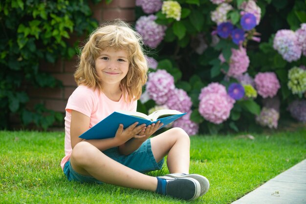 Linda criança adorável lendo livro fora de criança lendo livro no parque