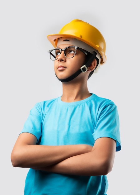 Linda criança asiática indiana feliz usando um capacete amarelo de construção ou capacete de segurança, isolado na parede branca segurando a planta