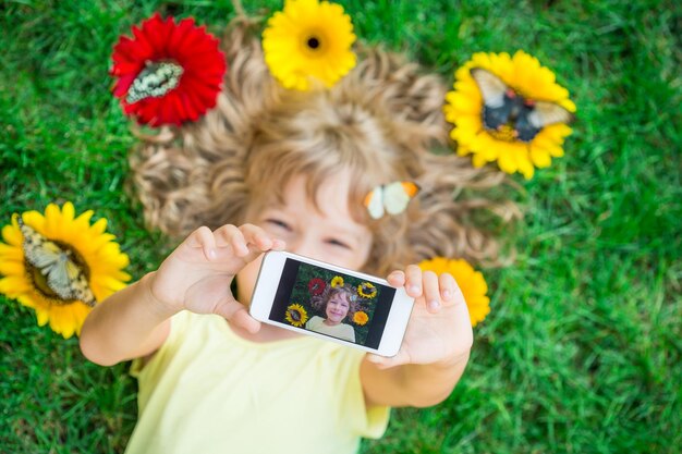 Linda criança com borboleta no parque primavera Criança feliz tomando selfie ao ar livre