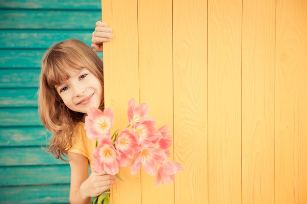 Linda criança com buquê de flores escondido atrás do conceito de dia das mães com fundo de madeira