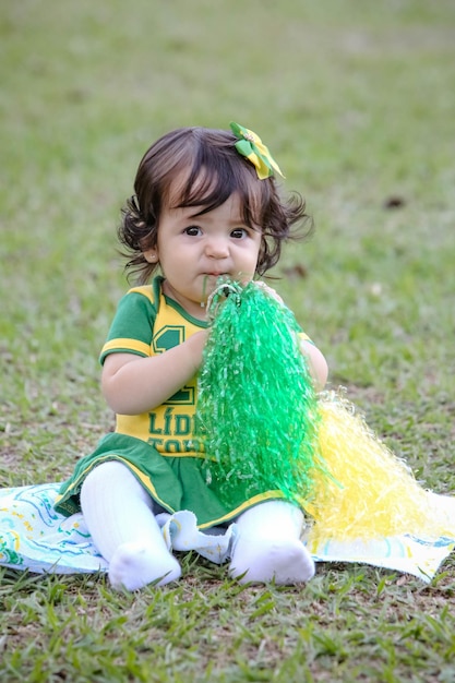 Linda criança da seleção brasileira de futebol em um parque vestida de verde e amarelo