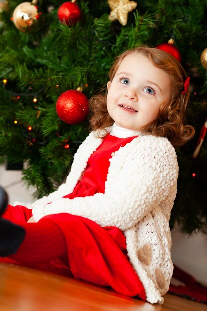 Foto linda criança pequena perto de árvore de natal.