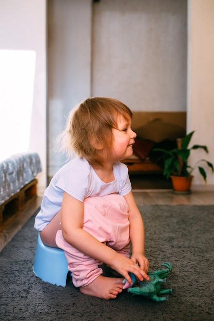 Linda criança pequena treinando penico brincando com seus brinquedos no penico