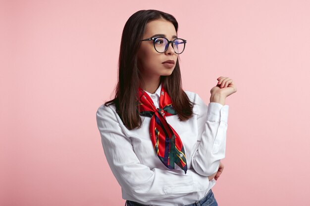 Linda dama con camisa blanca y anteojos aislados sobre pared rosa