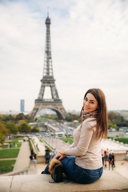 Linda dama fica na fronteira contra a torre eiffel Lady sorri e se diverte