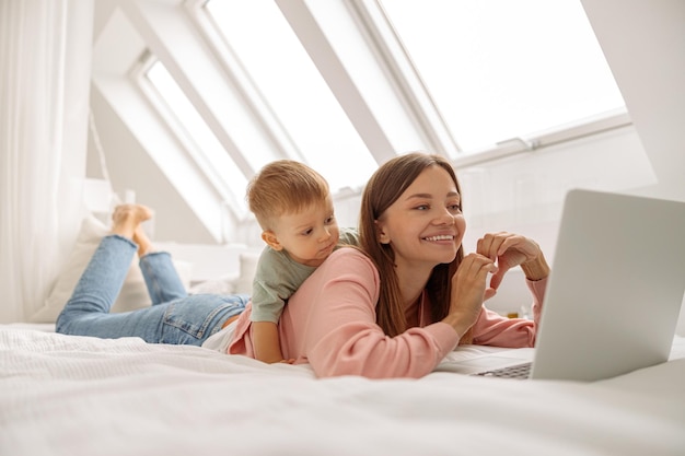 Linda dama usando una laptop mientras pasa tiempo con su bebé en casa