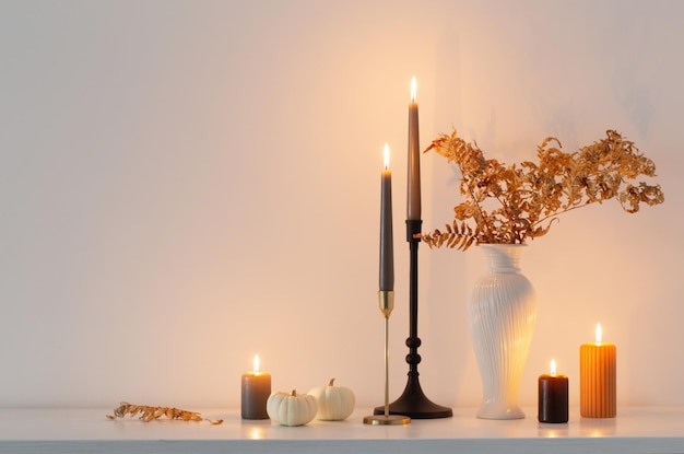 Linda decoração de outono com velas acesas no interior branco