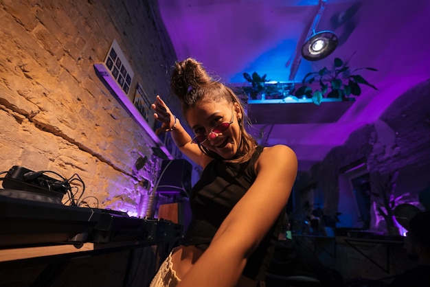 Foto linda dj feminina dançando techno em um pequeno clube