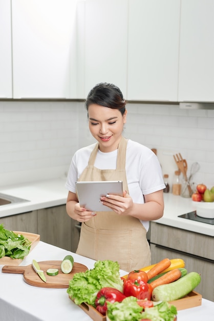 Linda dona de casa segurando tablet digital pesquisando receita aula de internet aula magistral cozinhar jantar em família delicioso