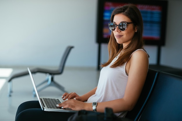 Linda e elegante empresária trabalhando em um computador em um aeroporto