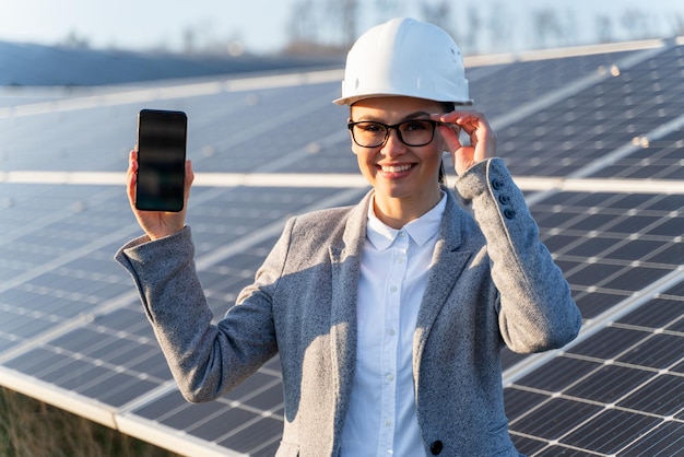 Linda e elegante engenheira no capacete está em frente ao painel solar ao ar livre