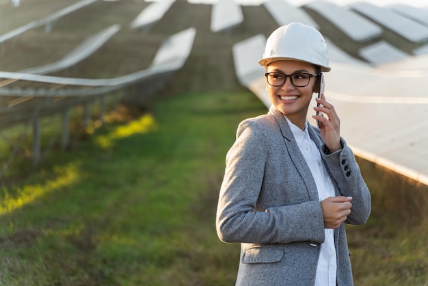 Linda e elegante mulher está discutindo um projeto inovador em seu smartphone na fazenda solar em Prado