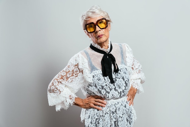 Linda e elegante velha influenciadora. Avó legal posando no estúdio, vestindo roupas da moda. Feliz senhora sênior comemorando e fazendo festa. Conceito sobre antiguidade e estilo de vida