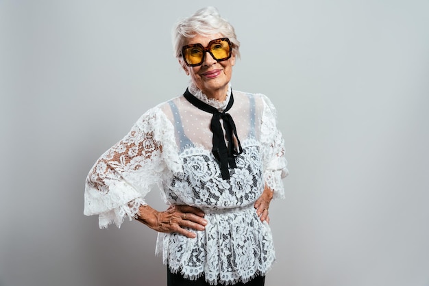 Linda e elegante velha influenciadora. Avó legal posando no estúdio, vestindo roupas da moda. Feliz senhora sênior comemorando e fazendo festa. Conceito sobre antiguidade e estilo de vida