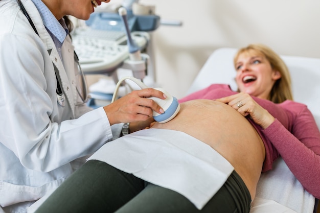 Foto linda e feliz futura mãe fazendo ultrassom na clínica pré-natal.