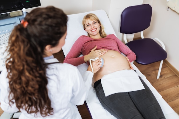 Linda e feliz futura mãe no exame ginecológico com equipamento médico de ultra-som.