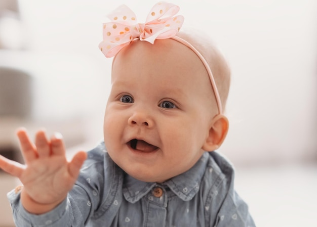 Linda e feliz menina de 6 meses com laço rosa rastejando dentro de casa Criança muito sorridente