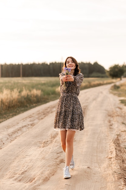 Linda e gentil adolescente em um vestido caminhando e relaxando na natureza no verão