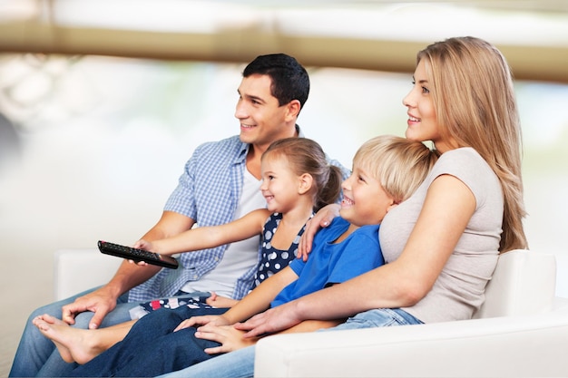 Linda e sorridente família adorável assistindo tv no fundo