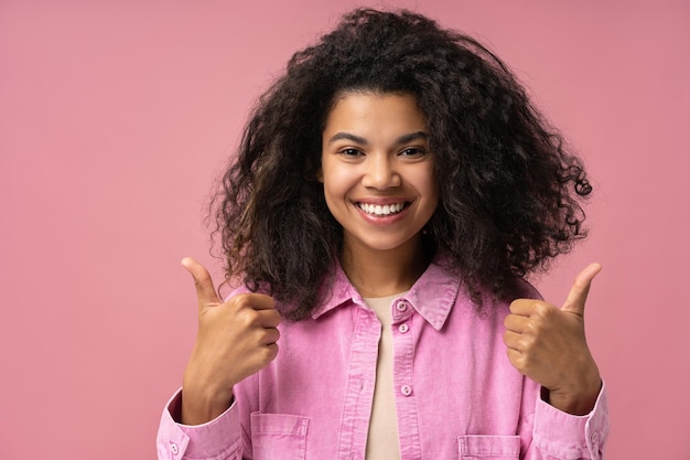 Linda e sorridente mulher afro-americana segurando grandes polegares isolados em boas notícias de fundo