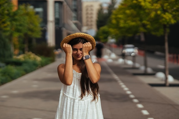 Linda em um vestido branco posa na rua