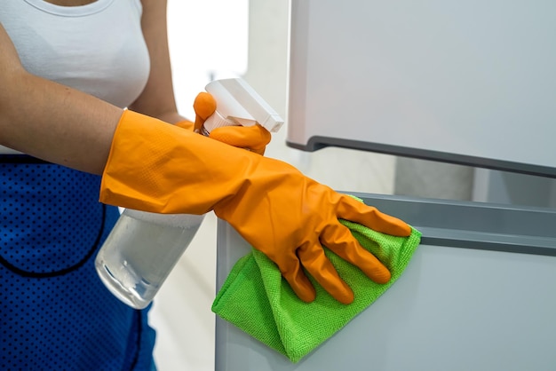 Linda empregada limpando portas de geladeira com pano