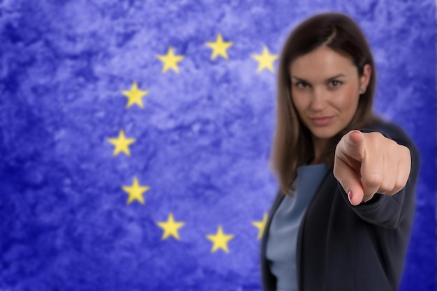 Linda empresária apontando o dedo para você, fundo da bandeira da UE.