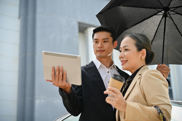 Linda empresária asiática trabalhando com uma arquitetura masculina usando tablet