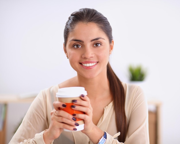 Linda empresária desfrutando de café no escritório brilhante