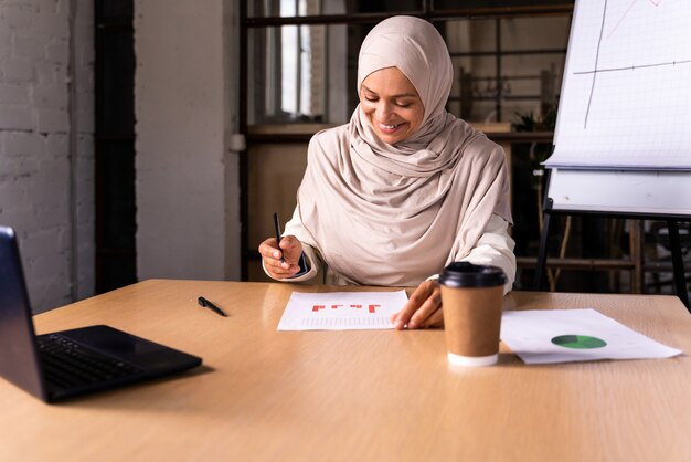 Linda empresária do oriente médio usando um hijab trabalhando em seu escritório